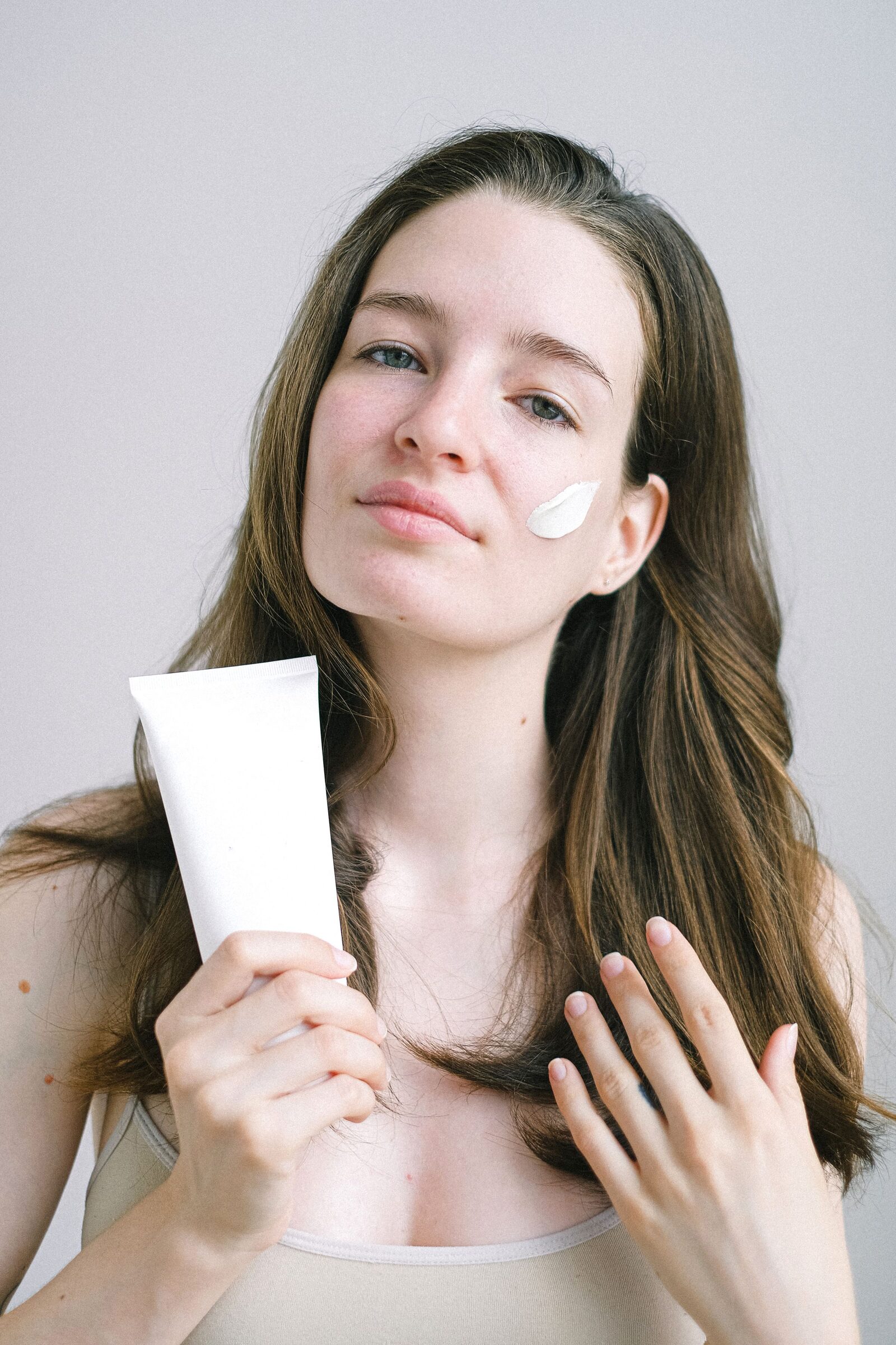 Model holding a plain white skincare tube