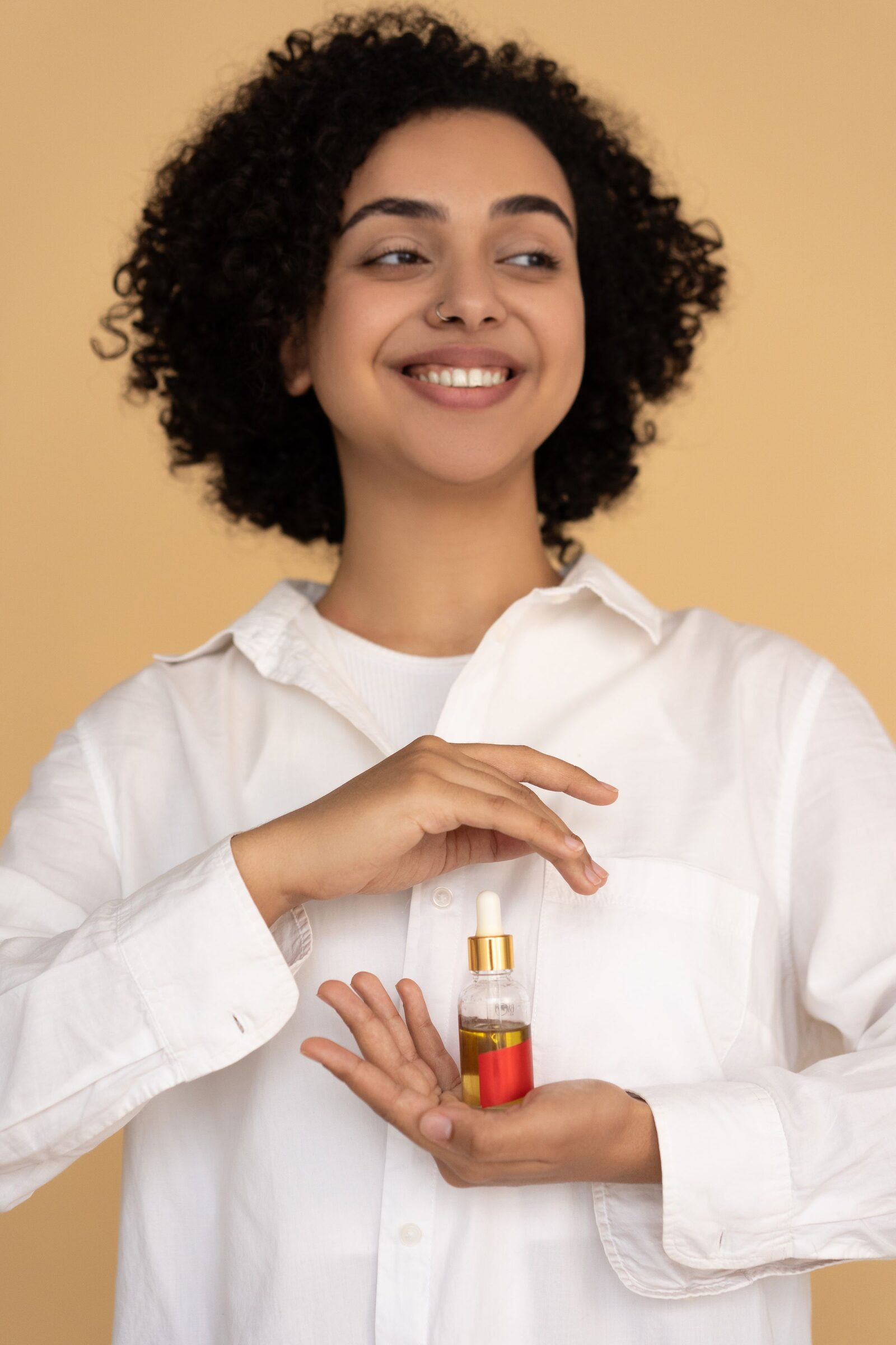 Model holding a dropper bottle against an orange background
